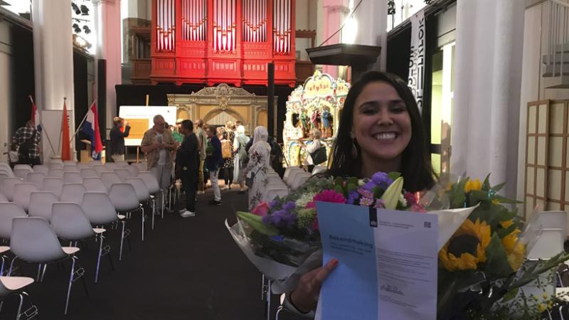 Manizha in Museum Speelklok in Utrecht met een grote bos bloemen en papieren in haar hand